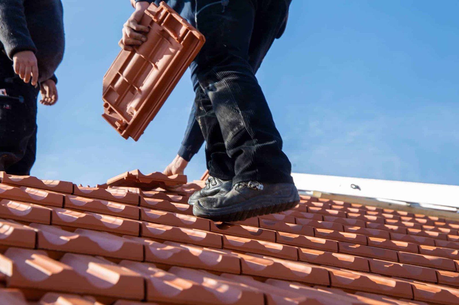 Roofing technician from AKM 941 Roofing installing shingles on a residential roof in Lee County, FL, demonstrating precision and safety with professional-grade equipment under bright daylight.