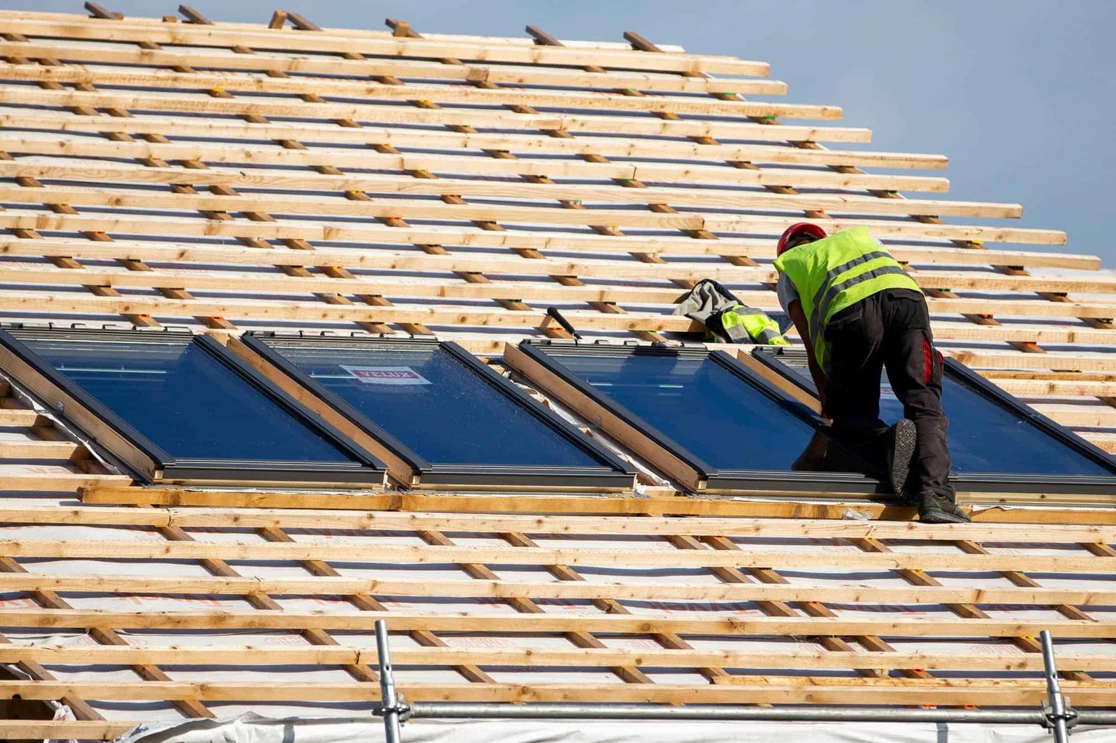 Professional roofer working on a residential rooftop in Lee County, FL, wearing safety gear and using tools to secure shingles under a clear sky — showcasing AKM Roofing’s craftsmanship and attention to detail