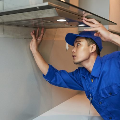 Young Vietnamese technician installing extractor hood in kitchen