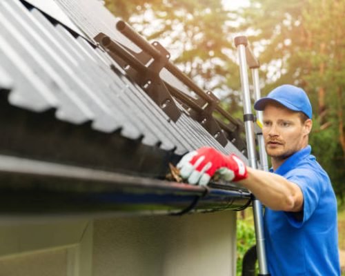 worker cleaning house gutter from leaves and dirt